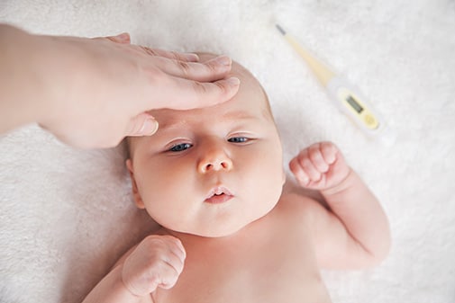 Ein Baby hat Babyschnupfen und erhöhte Temperatur. Dadurch kommt es auch oft zu einer verstopften Nase.